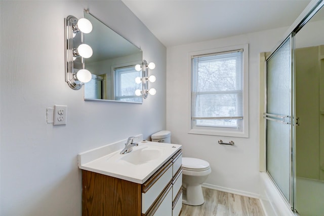 bathroom featuring a wealth of natural light, toilet, vanity, and wood finished floors