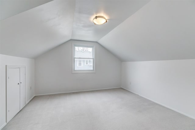 additional living space with baseboards, light carpet, and vaulted ceiling