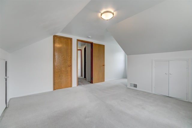 additional living space featuring light carpet, visible vents, baseboards, and lofted ceiling