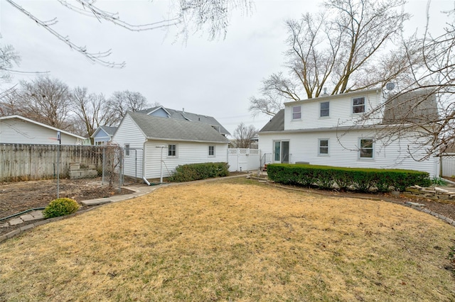 back of house with a gate, a yard, and fence