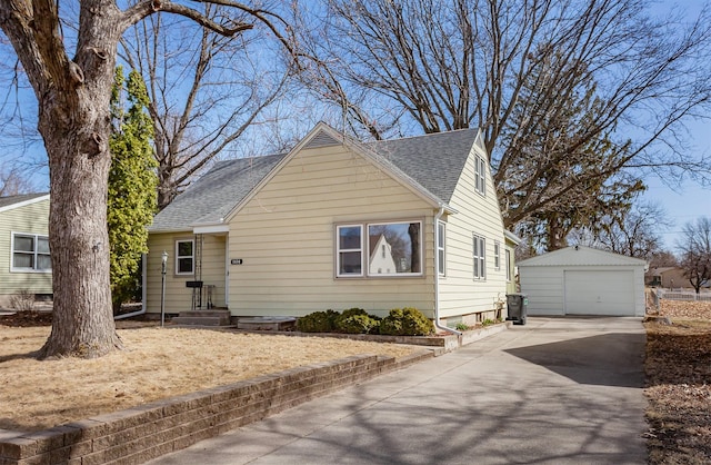 view of front of property featuring an outbuilding, a garage, driveway, and a shingled roof