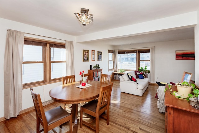 dining space with a baseboard heating unit, light wood-type flooring, and baseboards