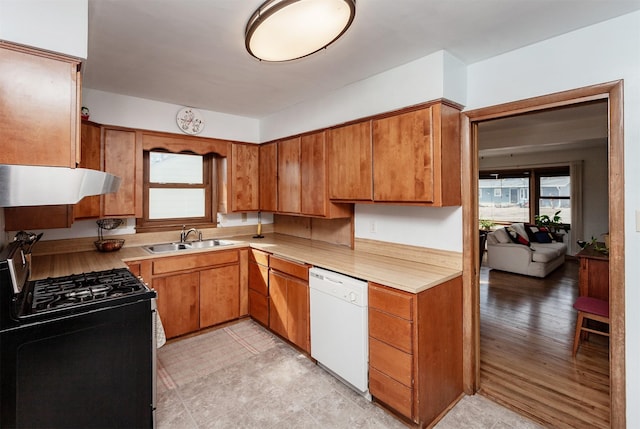 kitchen with a sink, under cabinet range hood, light countertops, dishwasher, and stainless steel gas range