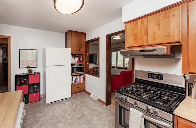 kitchen featuring visible vents, baseboards, under cabinet range hood, brown cabinets, and appliances with stainless steel finishes