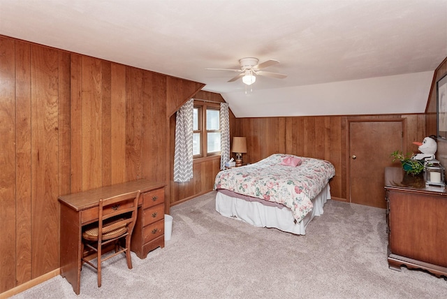 bedroom with ceiling fan, lofted ceiling, light carpet, and wood walls