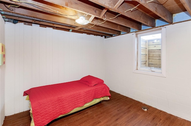 bedroom featuring wood finished floors and concrete block wall