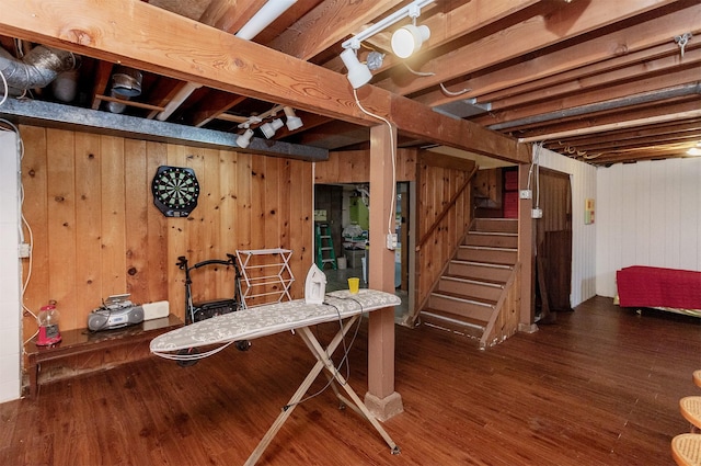 finished below grade area with stairway, wood walls, and wood finished floors