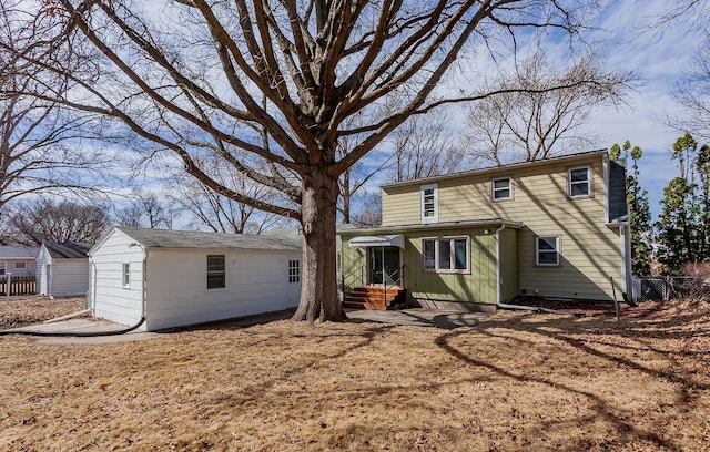 view of front facade with entry steps, an outbuilding, and fence