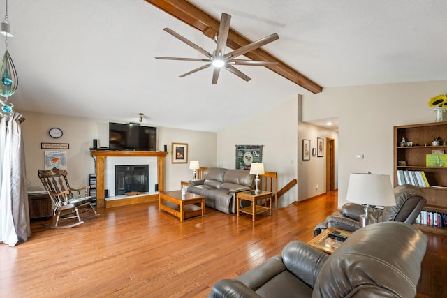 living room featuring a glass covered fireplace, vaulted ceiling with beams, light wood finished floors, and ceiling fan