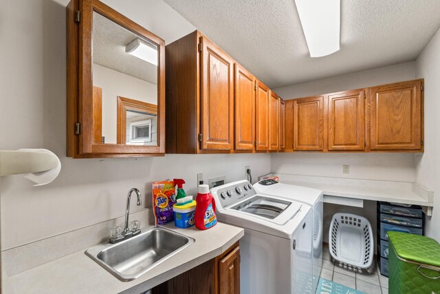 clothes washing area featuring a textured ceiling, cabinet space, independent washer and dryer, and a sink