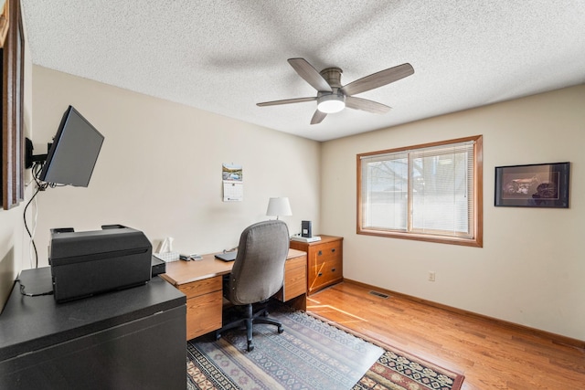 office space with baseboards, visible vents, ceiling fan, a textured ceiling, and light wood-type flooring