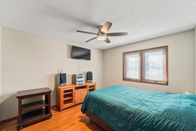 bedroom featuring a textured ceiling, ceiling fan, and light wood finished floors