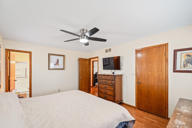 bedroom with visible vents, connected bathroom, light wood-type flooring, a textured ceiling, and a ceiling fan