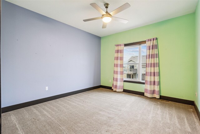 carpeted empty room featuring baseboards and a ceiling fan