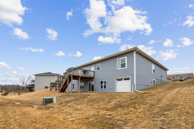 rear view of house featuring a deck, stairway, an attached garage, and a yard