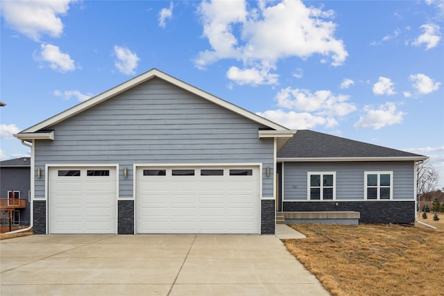 view of front facade with stone siding, concrete driveway, a garage, and a shingled roof