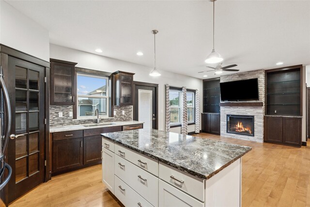 kitchen with tasteful backsplash, light wood finished floors, ceiling fan, dark brown cabinetry, and a sink