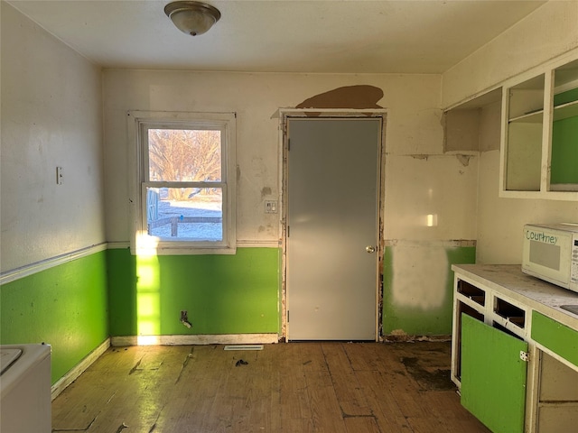 kitchen with white microwave, baseboards, and wood-type flooring