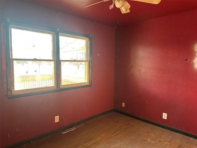 spare room featuring visible vents, baseboards, wood finished floors, and a ceiling fan