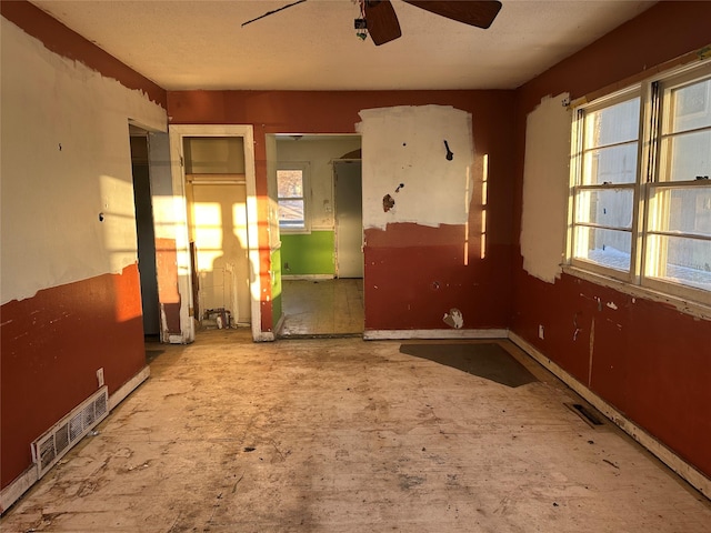 unfurnished room featuring baseboards, visible vents, and ceiling fan