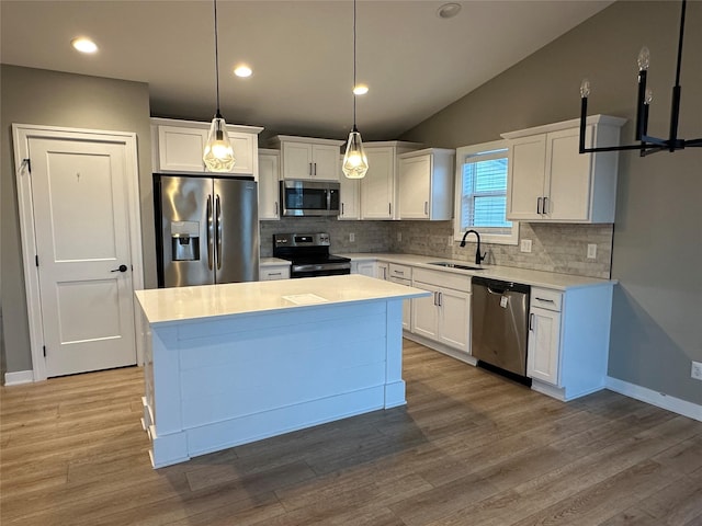 kitchen with white cabinets, appliances with stainless steel finishes, light countertops, and wood finished floors