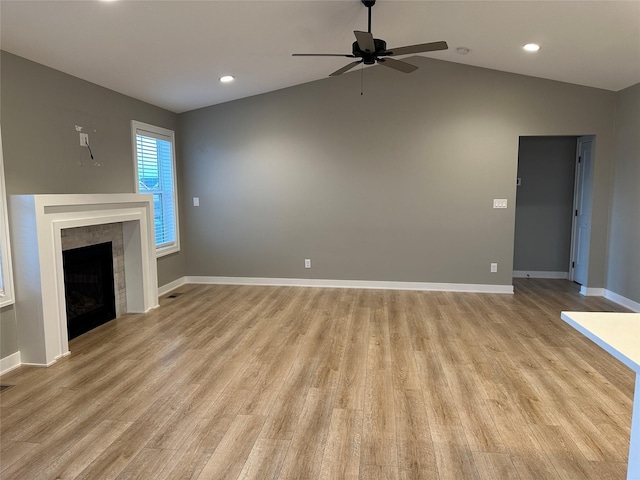 unfurnished living room featuring a ceiling fan, baseboards, light wood finished floors, lofted ceiling, and a fireplace