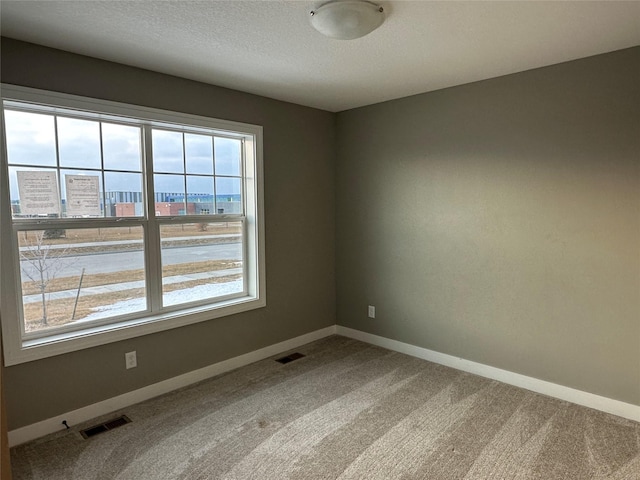 unfurnished room featuring light carpet, visible vents, a textured ceiling, and baseboards