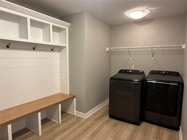 clothes washing area featuring laundry area, baseboards, light wood-type flooring, and washing machine and clothes dryer