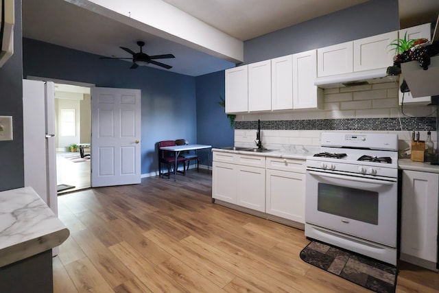 kitchen with light wood finished floors, white cabinets, white appliances, and a sink