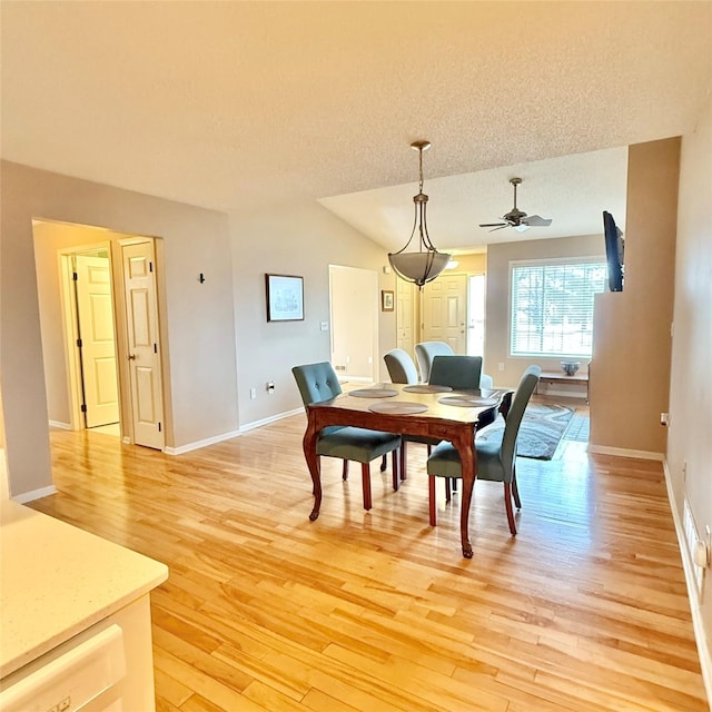 dining area featuring baseboards, a ceiling fan, light wood-type flooring, and a textured ceiling