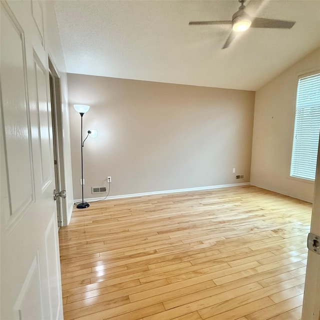 unfurnished room featuring baseboards, visible vents, ceiling fan, vaulted ceiling, and light wood-type flooring