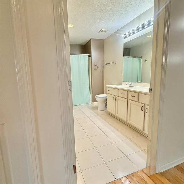 bathroom with visible vents, toilet, a textured ceiling, tile patterned flooring, and vanity