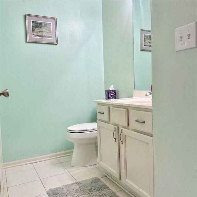 half bathroom with vanity, tile patterned floors, toilet, and baseboards