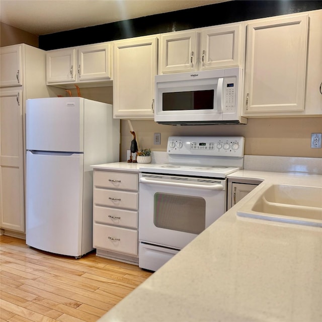 kitchen with light wood-style flooring, a sink, white appliances, white cabinets, and light countertops