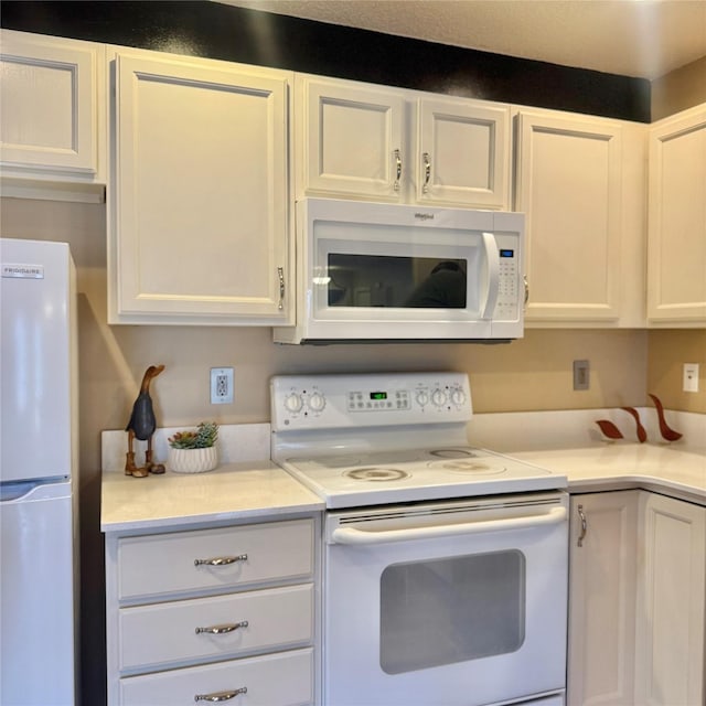 kitchen with white appliances, white cabinets, and light countertops