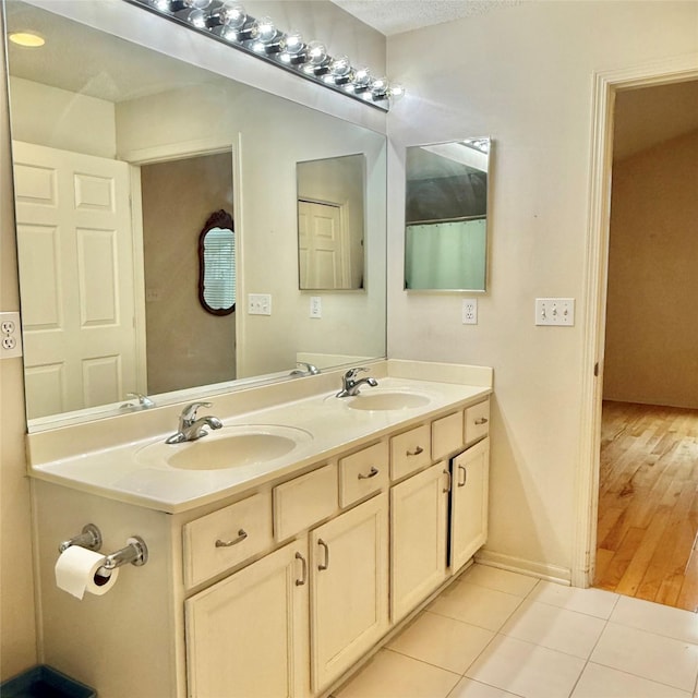 bathroom with tile patterned floors, double vanity, a textured ceiling, and a sink