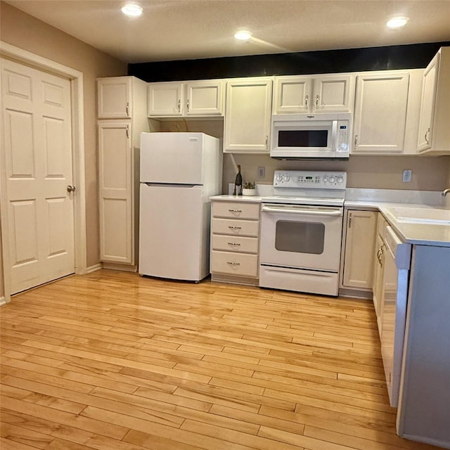 kitchen with light wood-style flooring, a sink, white appliances, white cabinets, and light countertops