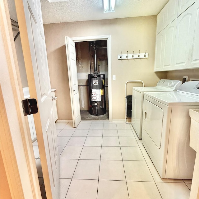 laundry area featuring a textured ceiling, water heater, cabinet space, light tile patterned floors, and washing machine and clothes dryer