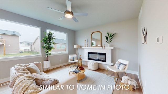 136 Creekside Dr, Bondurant, IA 50035 - living room featuring wood finished floors, a tiled fireplace, baseboards, and a ceiling fan