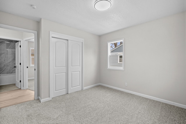 unfurnished bedroom with carpet flooring, baseboards, a closet, and a textured ceiling