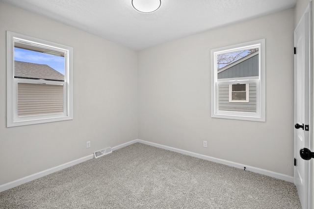 carpeted spare room featuring baseboards and visible vents