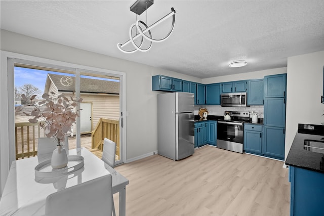 kitchen with dark countertops, blue cabinets, light wood finished floors, and stainless steel appliances