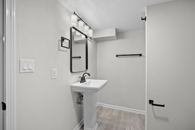 bathroom featuring a sink, wood finished floors, baseboards, and a textured ceiling