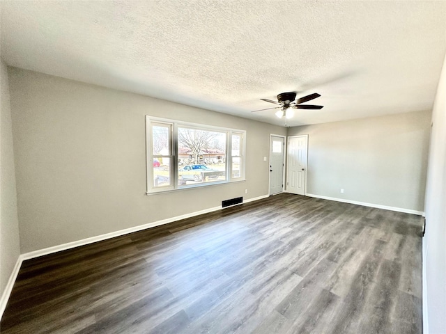 spare room featuring dark wood finished floors, a ceiling fan, baseboards, and a textured ceiling