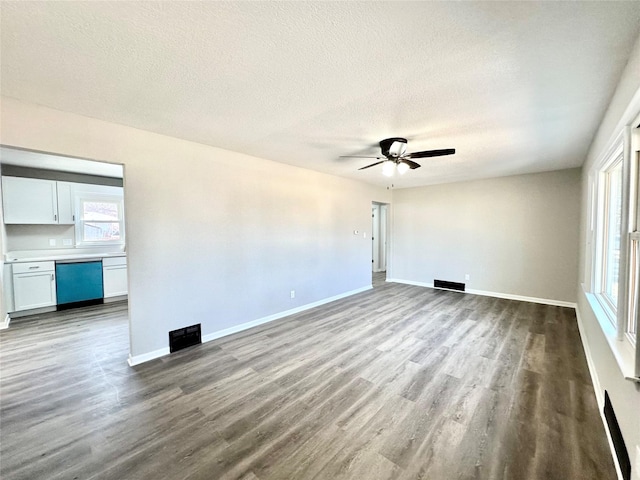 unfurnished room with a textured ceiling, wood finished floors, baseboards, and ceiling fan