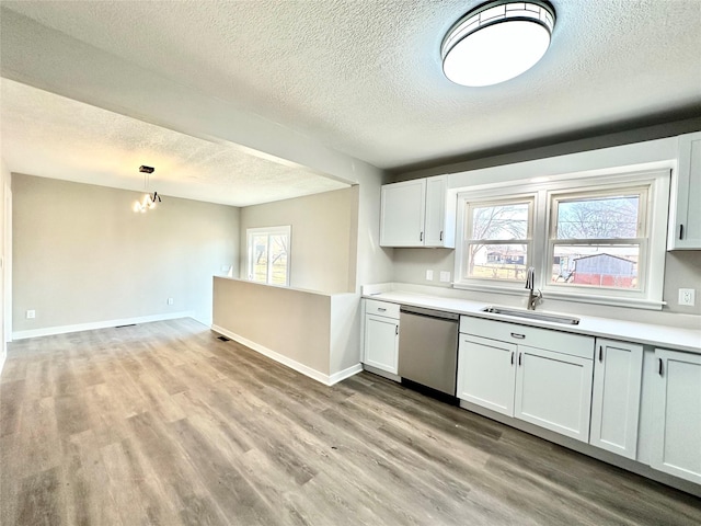 kitchen with light wood-style flooring, a sink, stainless steel dishwasher, light countertops, and baseboards