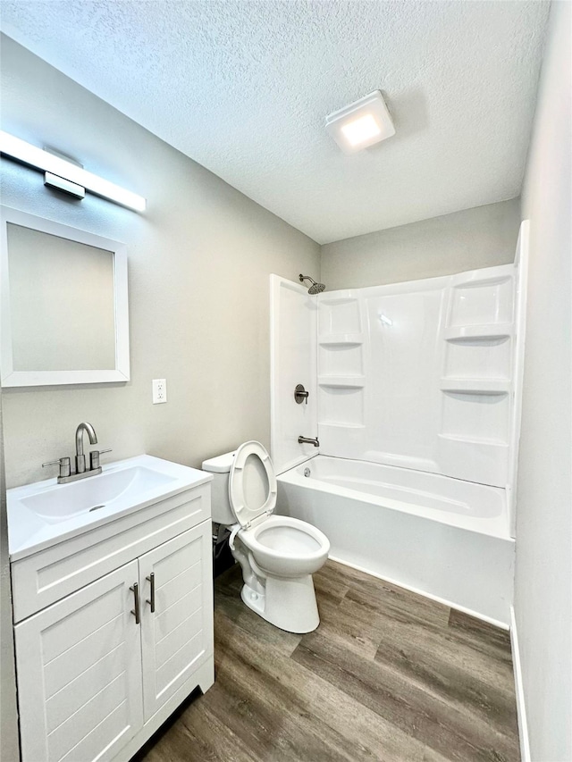 full bath featuring vanity, wood finished floors, shower / washtub combination, a textured ceiling, and toilet