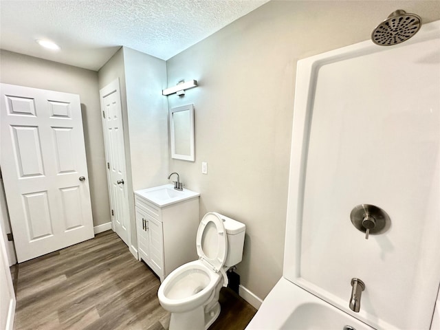 bathroom with vanity, wood finished floors, baseboards, a textured ceiling, and toilet