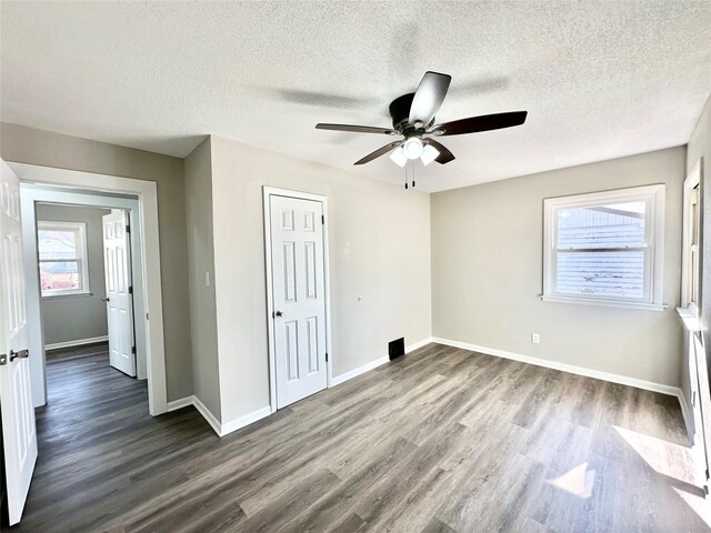 unfurnished bedroom featuring a closet, baseboards, dark wood-style floors, and a ceiling fan