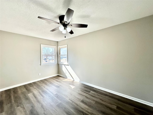 spare room with a textured ceiling, a ceiling fan, dark wood-type flooring, and baseboards